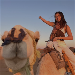 Nicole riding a camel at sunset